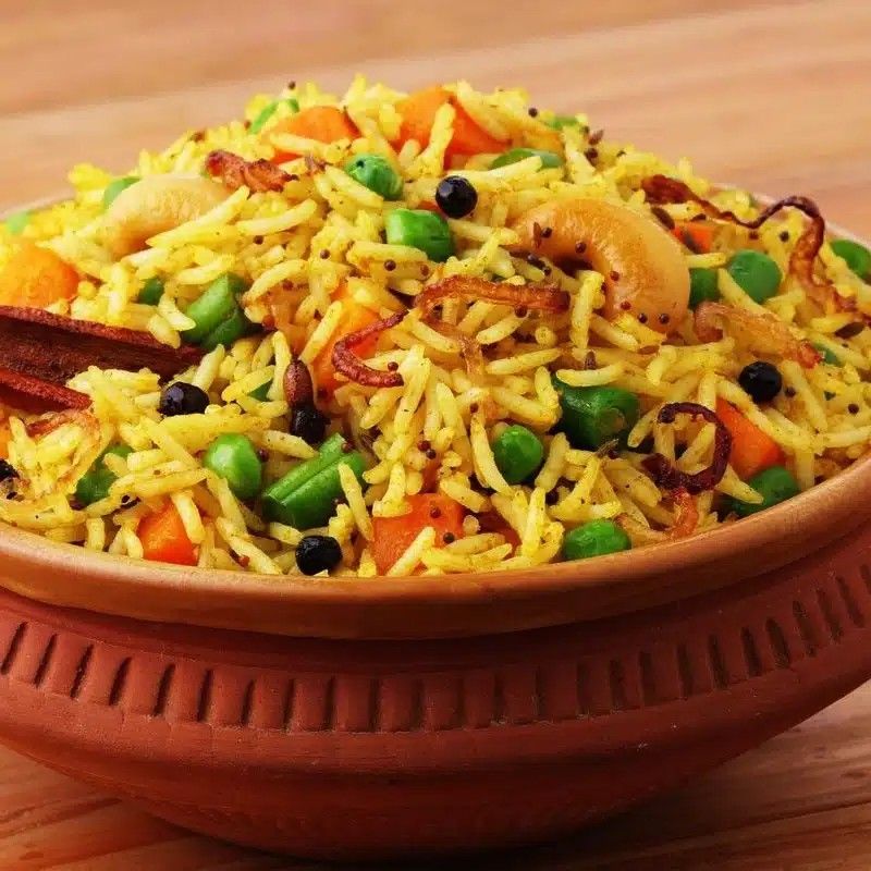 Vegetable biryani with peas and carrots in a clay bowl